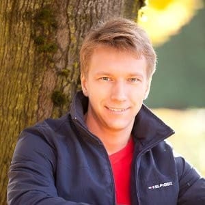 A man in a blue jacket leaning against a tree in the San Francisco Bay Area.