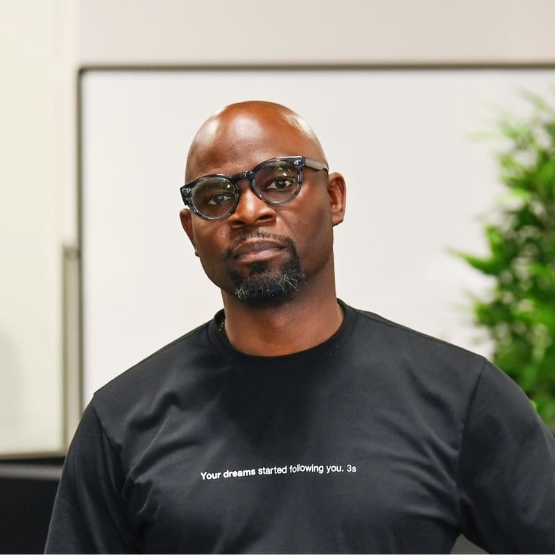 A bald man from the San Francisco Bay Area, wearing glasses and a black t-shirt.