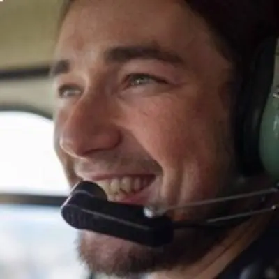 A man smiling while sitting in a helicopter over the San Francisco Bay Area.