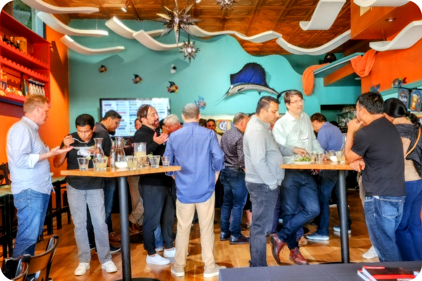 Men gather around a table in a restaurant.