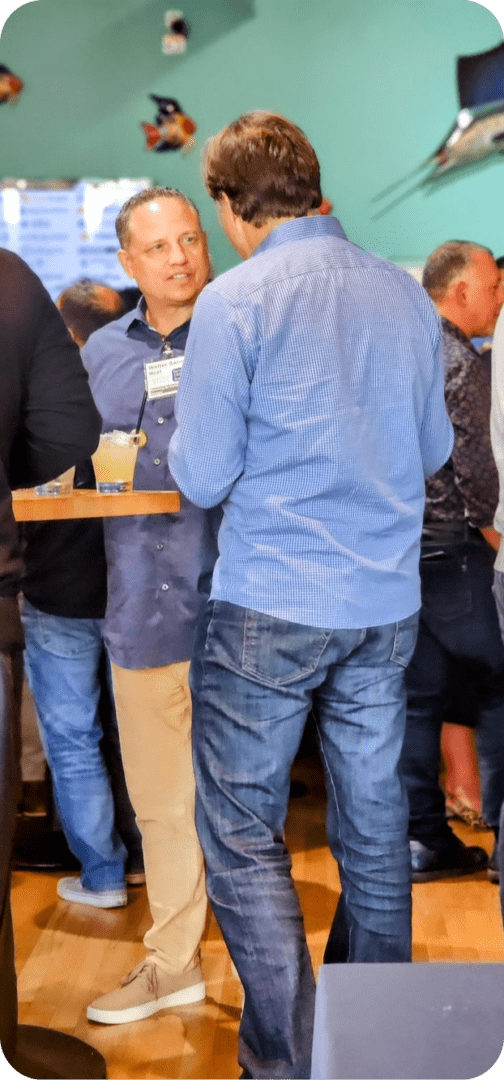 Two men in casual wear stand together.